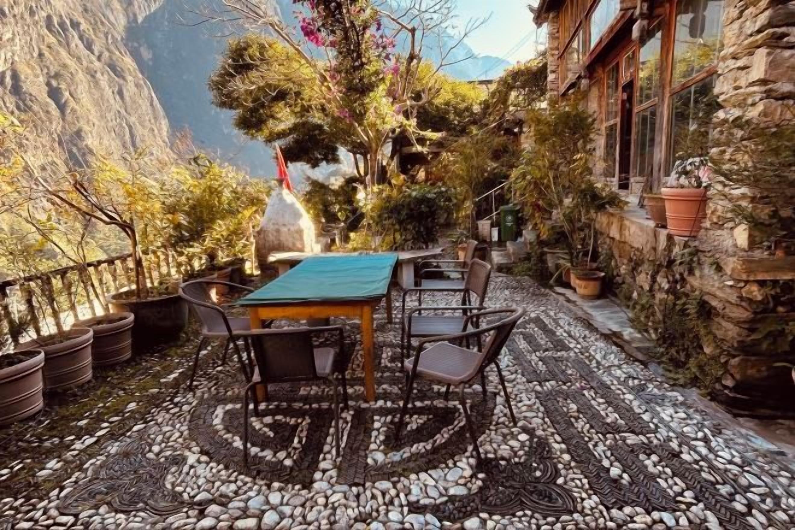 An outdoor seating area with a table and chairs, surrounded by potted plants and a stone wall.