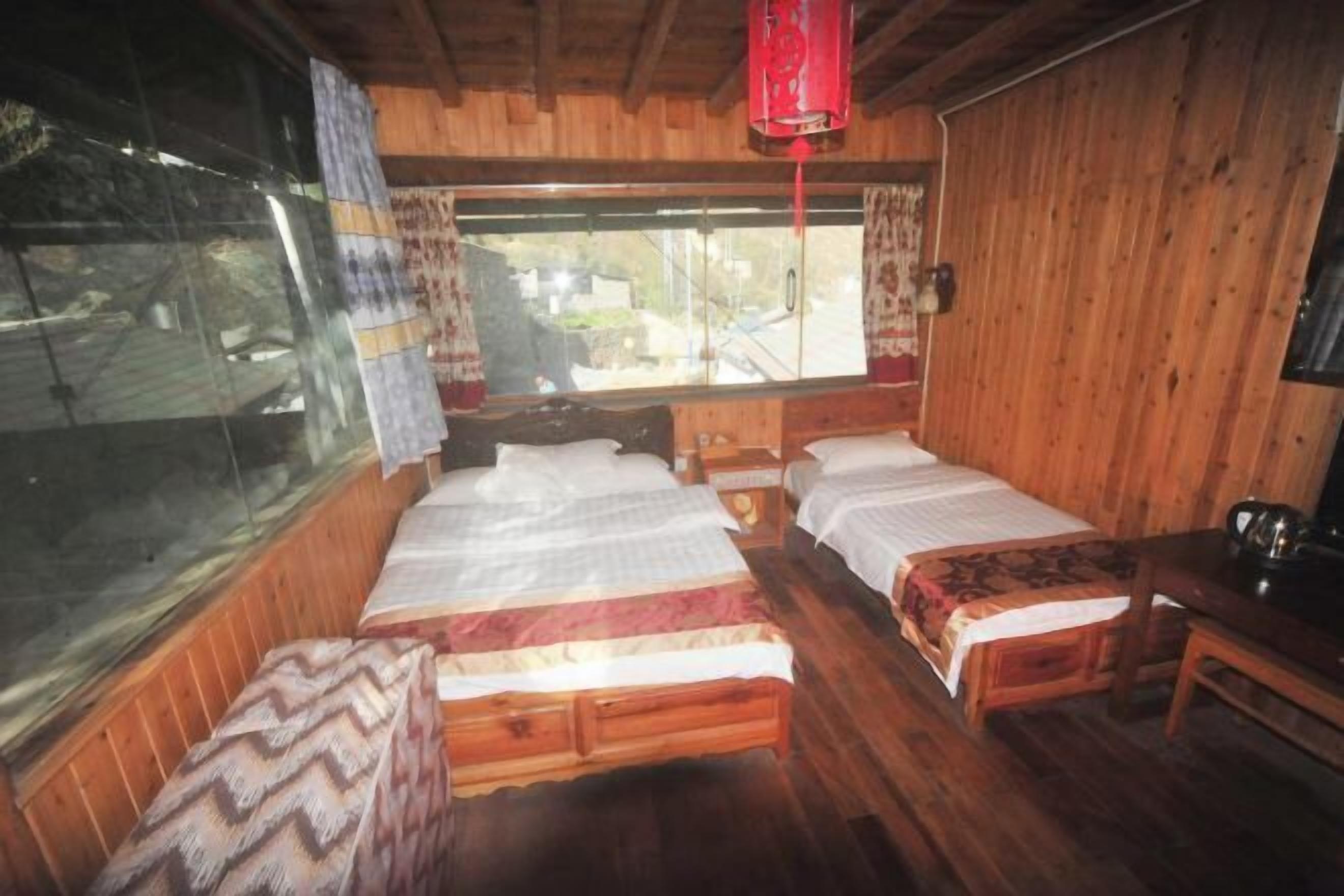 Ein Zimmer einer Holzhütte mit zwei Betten, einem Tisch und einem Fenster.