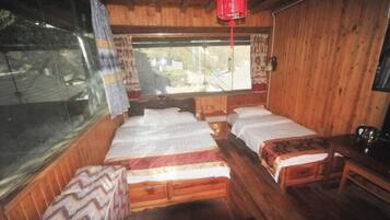 Ein Zimmer einer Holzhütte mit zwei Betten, einem Tisch und einem Fenster.