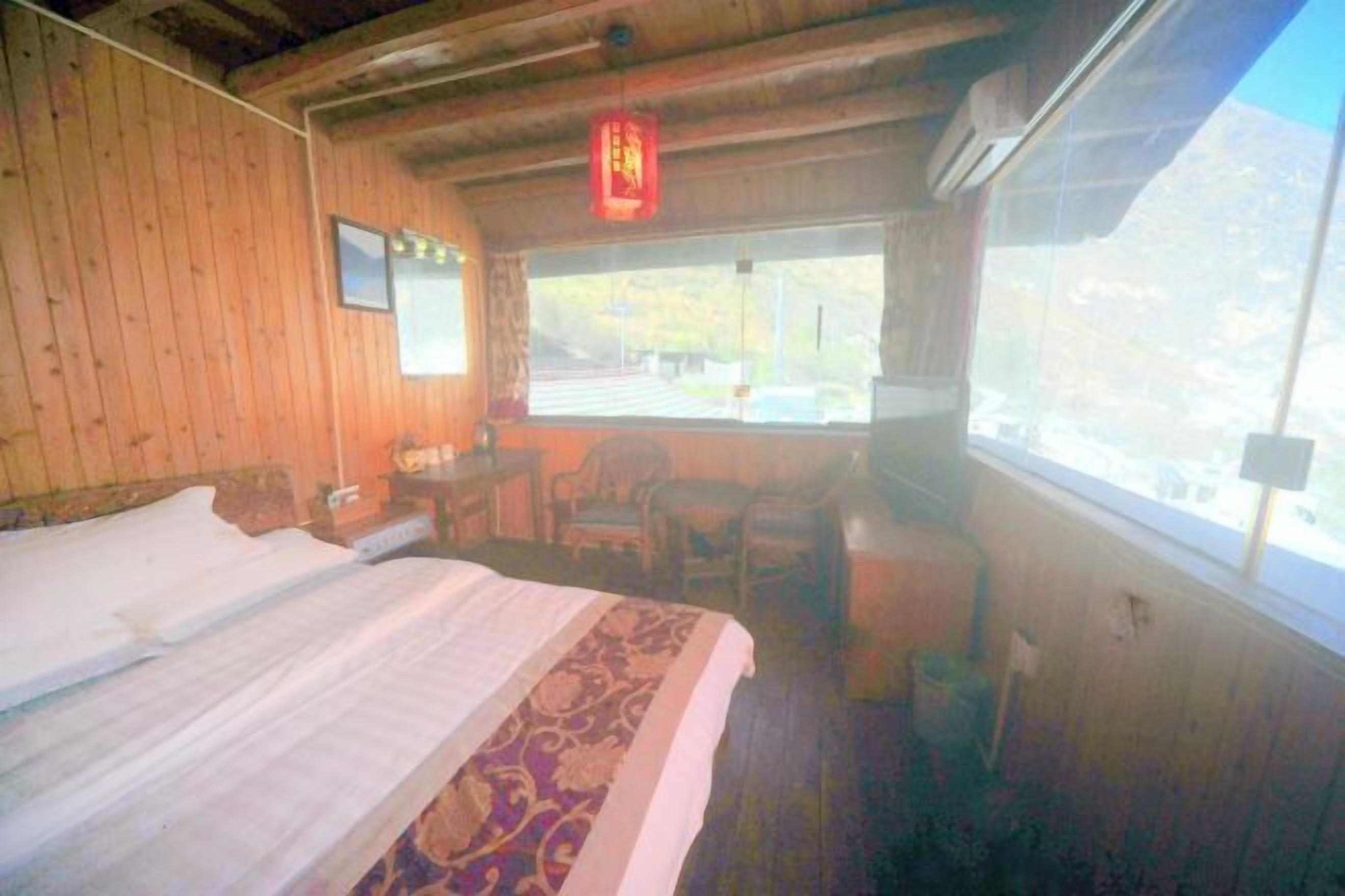 Ein Zimmer mit Holzboden, einem Bett, einem Schreibtisch und einem Fenster.