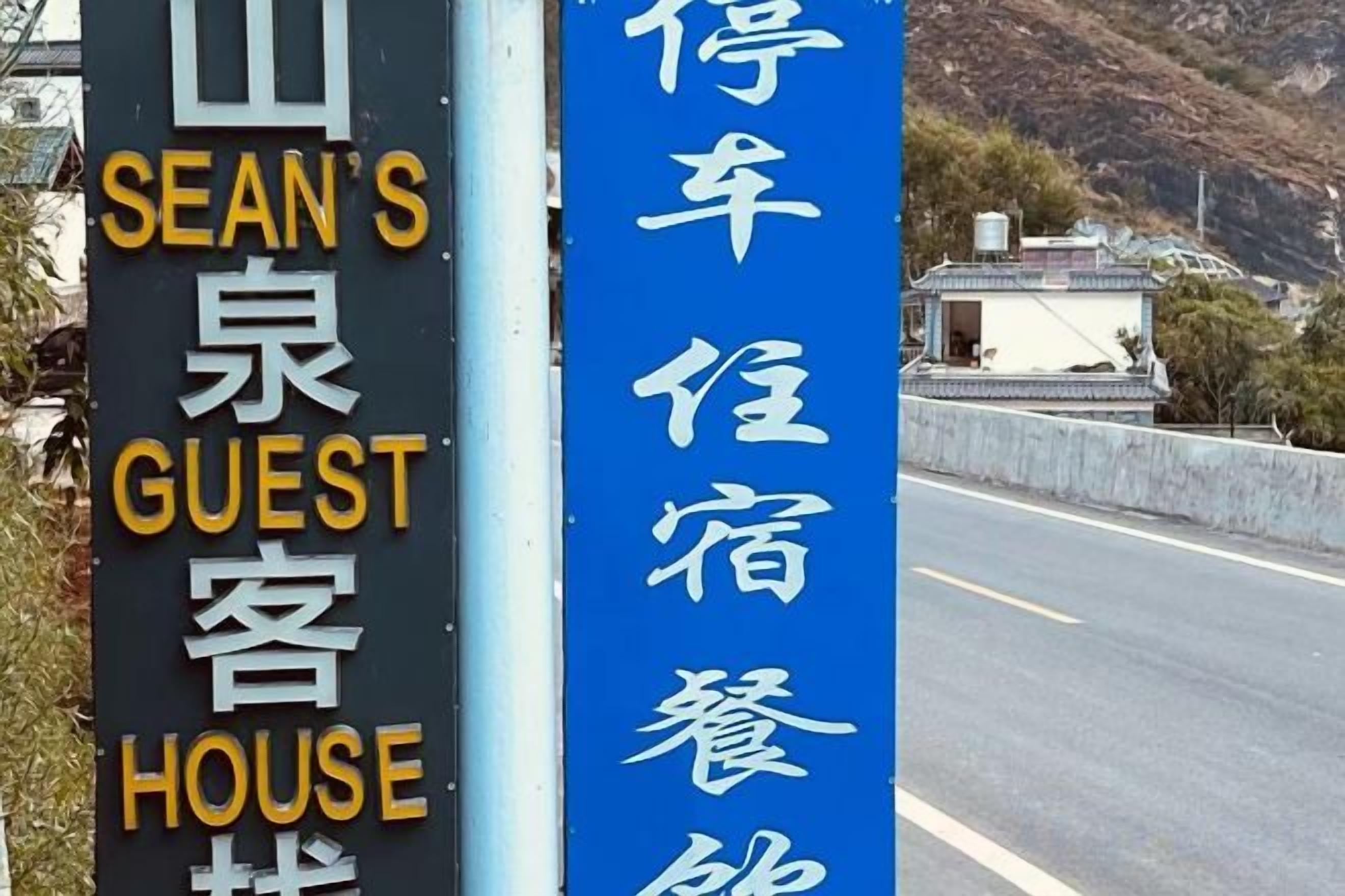 Un cartel que indica 'SEAN'S GUEST HOUSE' con un cartel vertical azul para 'RESTAURANT' a su lado.
