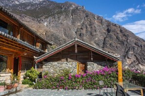 A traditional wooden building with a stone facade, set against a mountainous backdrop. - Sean’s Guesthouse (Shangri-La)