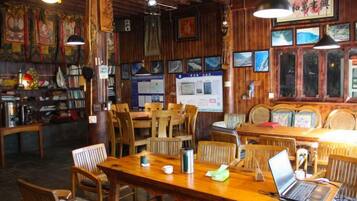 A restaurant interior with wooden furniture, tables, and chairs, and a laptop on one table.