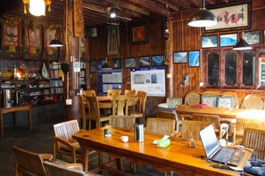 A restaurant interior with wooden furniture, tables, and chairs, and a laptop on one table. - Sean’s Guesthouse (Shangri-La)