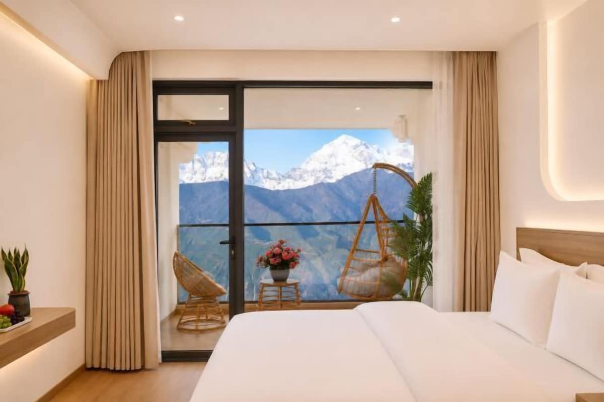 A bedroom with a bed, a hanging chair, and a view of mountains.