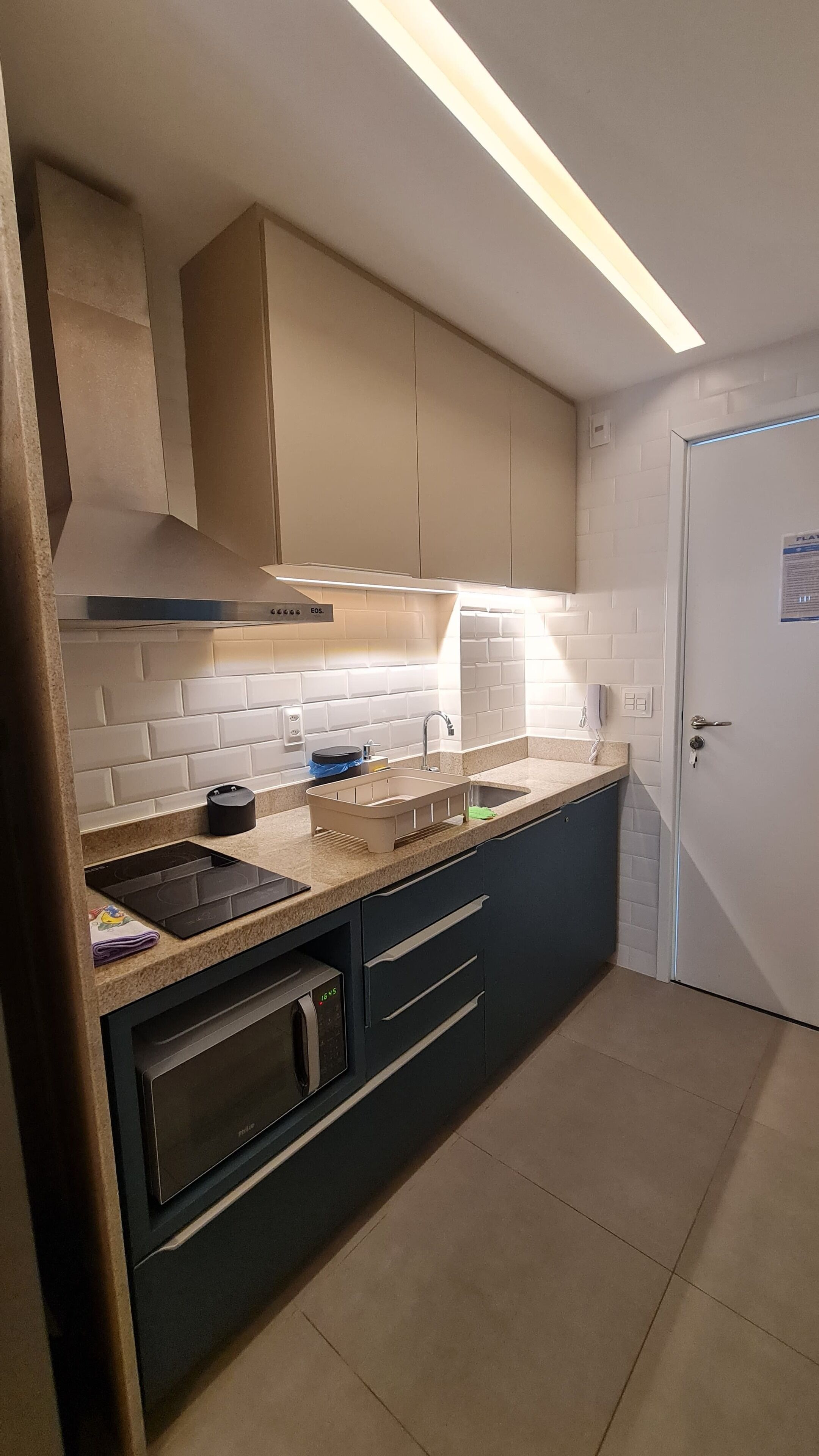 A kitchen with a built-in oven, a sink, and a microwave.