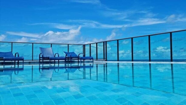 Une piscine à débordement à l’eau d’un bleu cristallin, offrant une vue sur l’océan.