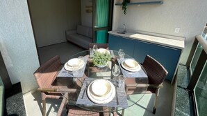 Un coin repas avec une table en verre, des chaises en osier et un meuble bleu avec un évier.