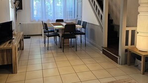 Un vaste espace de vie comprenant une table à manger, des chaises, un téléviseur et un escalier menant à l’étage supérieur.