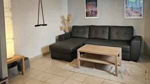 Un salon moderne avec un canapé d’angle, une table basse en bois et un sol carrelé.