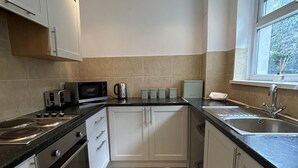 Una cucina moderna con piano cottura, microonde, tostapane, bollitore e lavello.