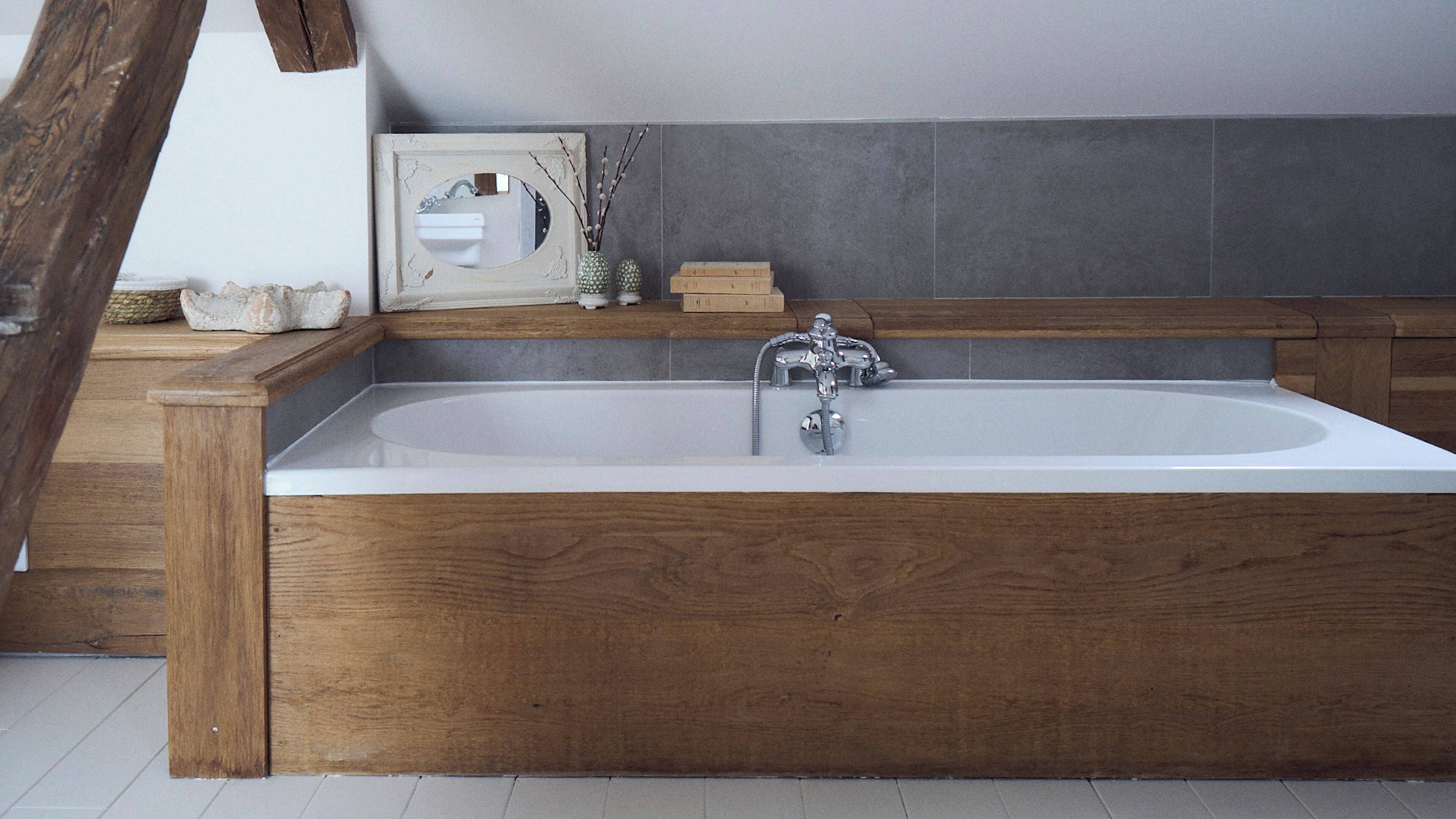 A modern bathroom with a wooden bathtub, a white sink, and a mirror.