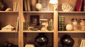 A wooden bookshelf with various books, a globe, decorative items, and two vases. - Maison Mouche  (Beaumont-en-Auge)