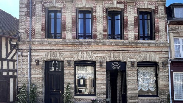 Un edificio histórico con múltiples ventanas y un letrero que dice "MAISON DE LA MOUCHE".