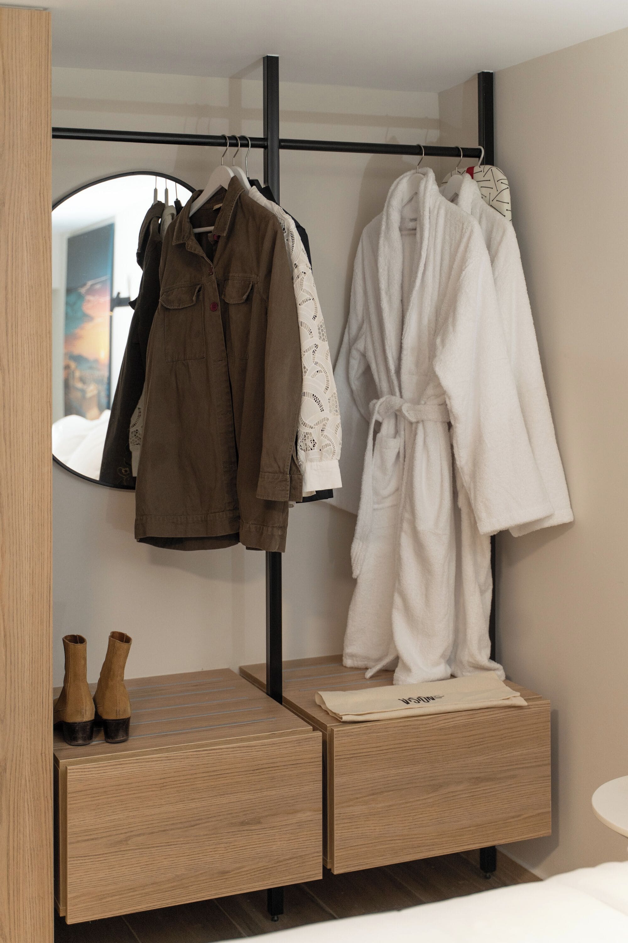 Ein modernes Badezimmer mit einem Holzkosmetikschrank, einem Spiegel und einem Kleiderständer mit Bademantel und Jacke.