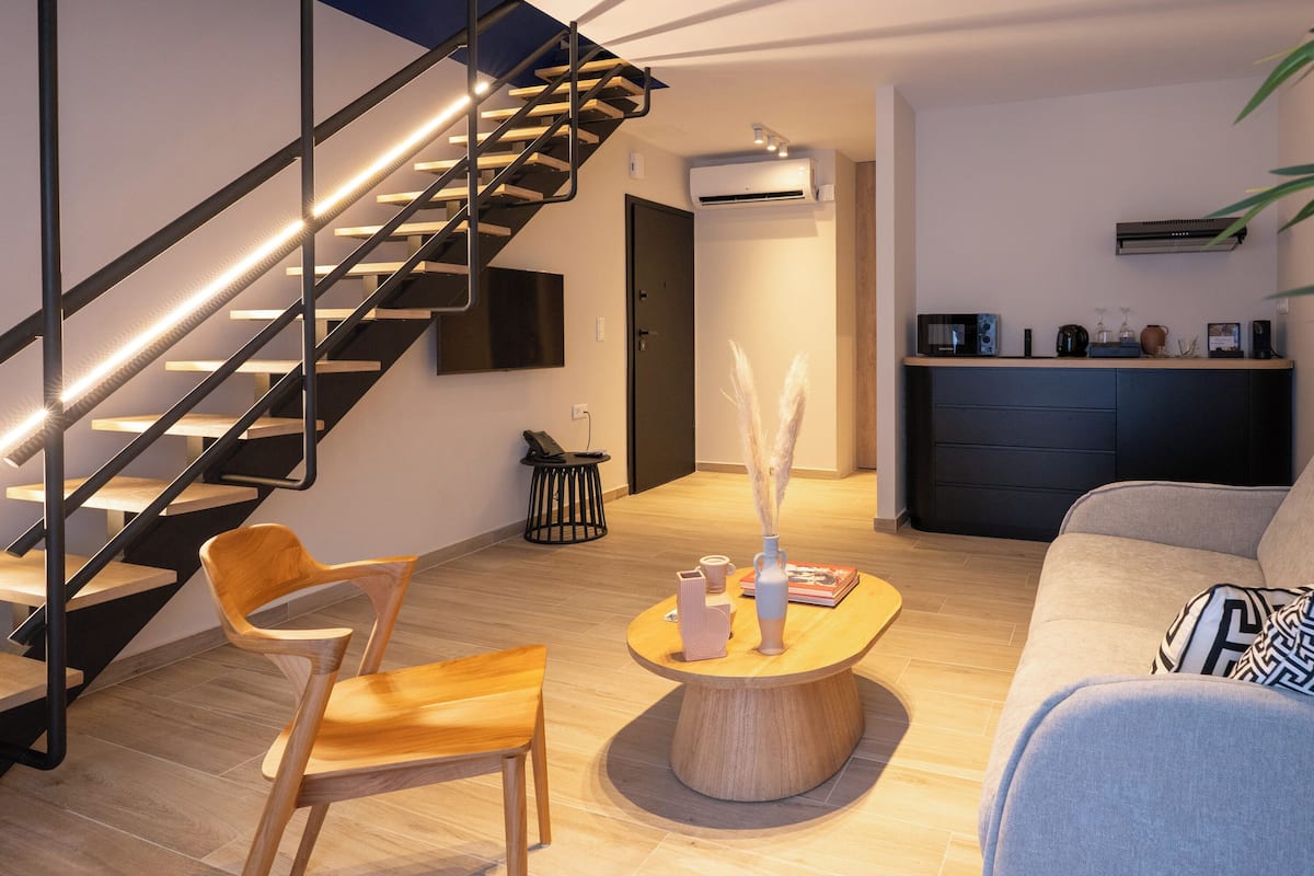 A modern living room with a wooden staircase, a round coffee table, and a sofa.