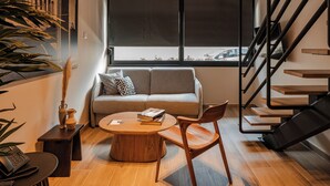 A modern living room with a sofa, a coffee table, and a staircase. - Vision Lavraga (Athens)
