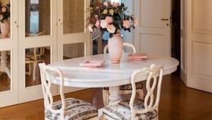 A dining area with a round table, white chairs, and a vase of flowers. - Cantaia Estate (Monte San Pietro)