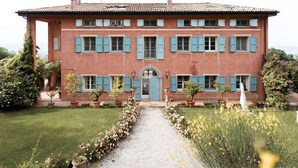 A large, two-story building with a symmetrical facade, multiple windows with shutters, and a central entrance with a door. - Cantaia Estate (Monte San Pietro)