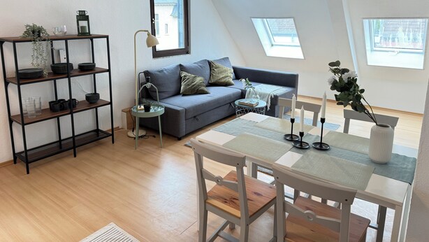 A modern loft apartment with a grey sofa, a dining table with chairs, a black metal shelving unit, and a skylight. - Erholung pur am Rhein (Sankt Goar)