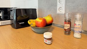 A kitchen counter with a bowl of fruit, a coffee maker, and two spice jars. - Erholung pur am Rhein (Sankt Goar)