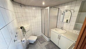 A bathroom with white tiles, a shower, a sink, and a toilet. - Erholung pur am Rhein (Sankt Goar)