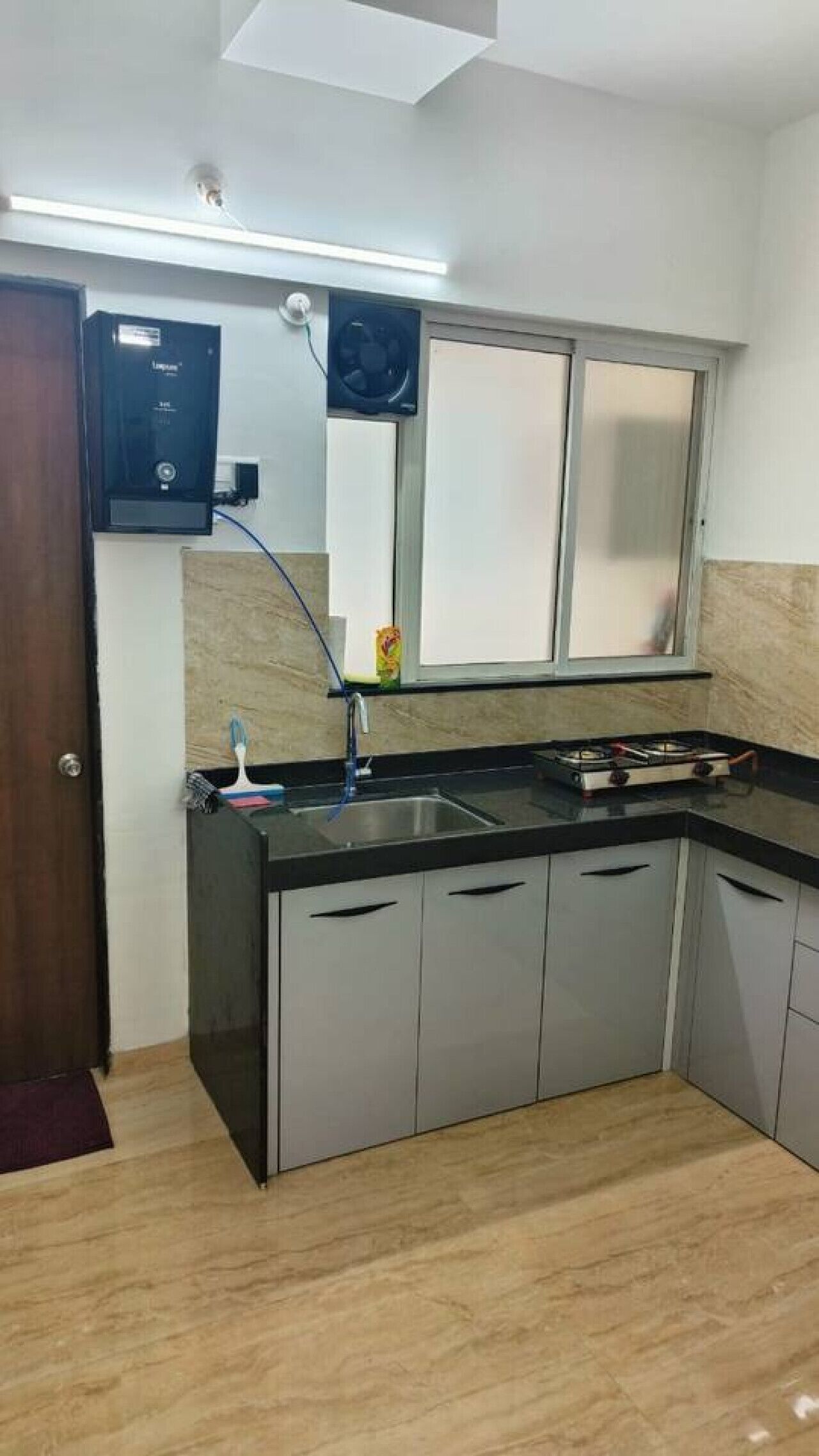 Een keuken met een ingebouwde vaatwasser, een spoelbak en een raam boven het aanrecht.