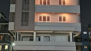 A multi-story building with balconies, a garage, and a flat roof. - Owl's Retreat: 2BHK Modern AC Flat in Wakad, Pune (Pimpri-Chinchwad)