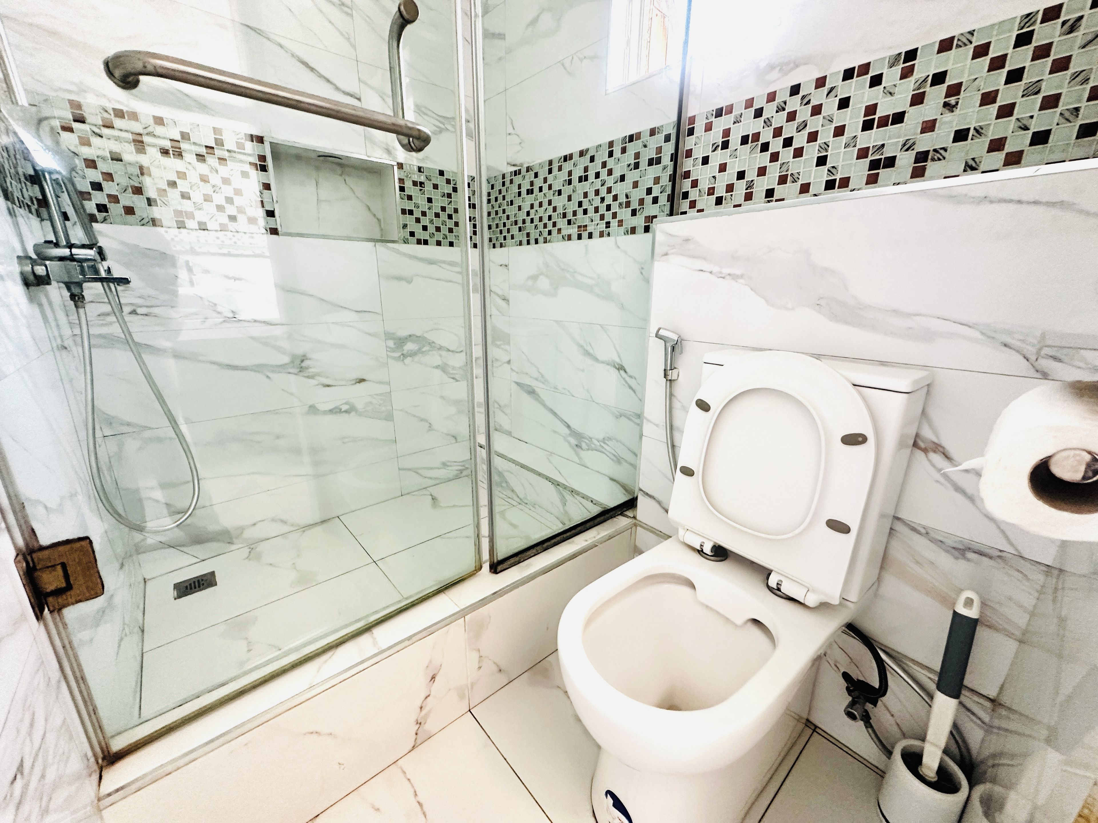 A bathroom with a glass-enclosed shower, a toilet, and a bidet.