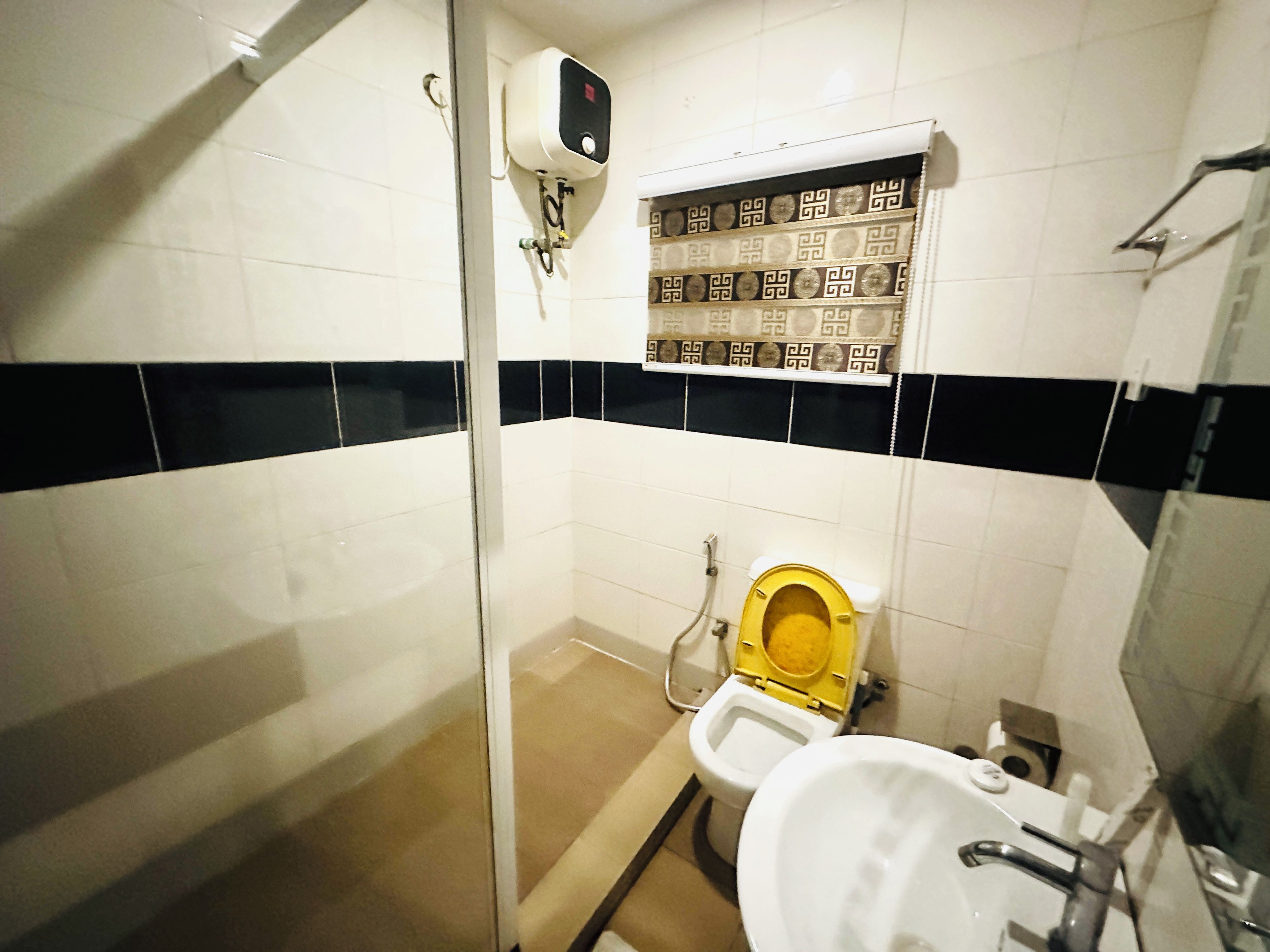 A bathroom with a toilet, a shower area, and a hand dryer.