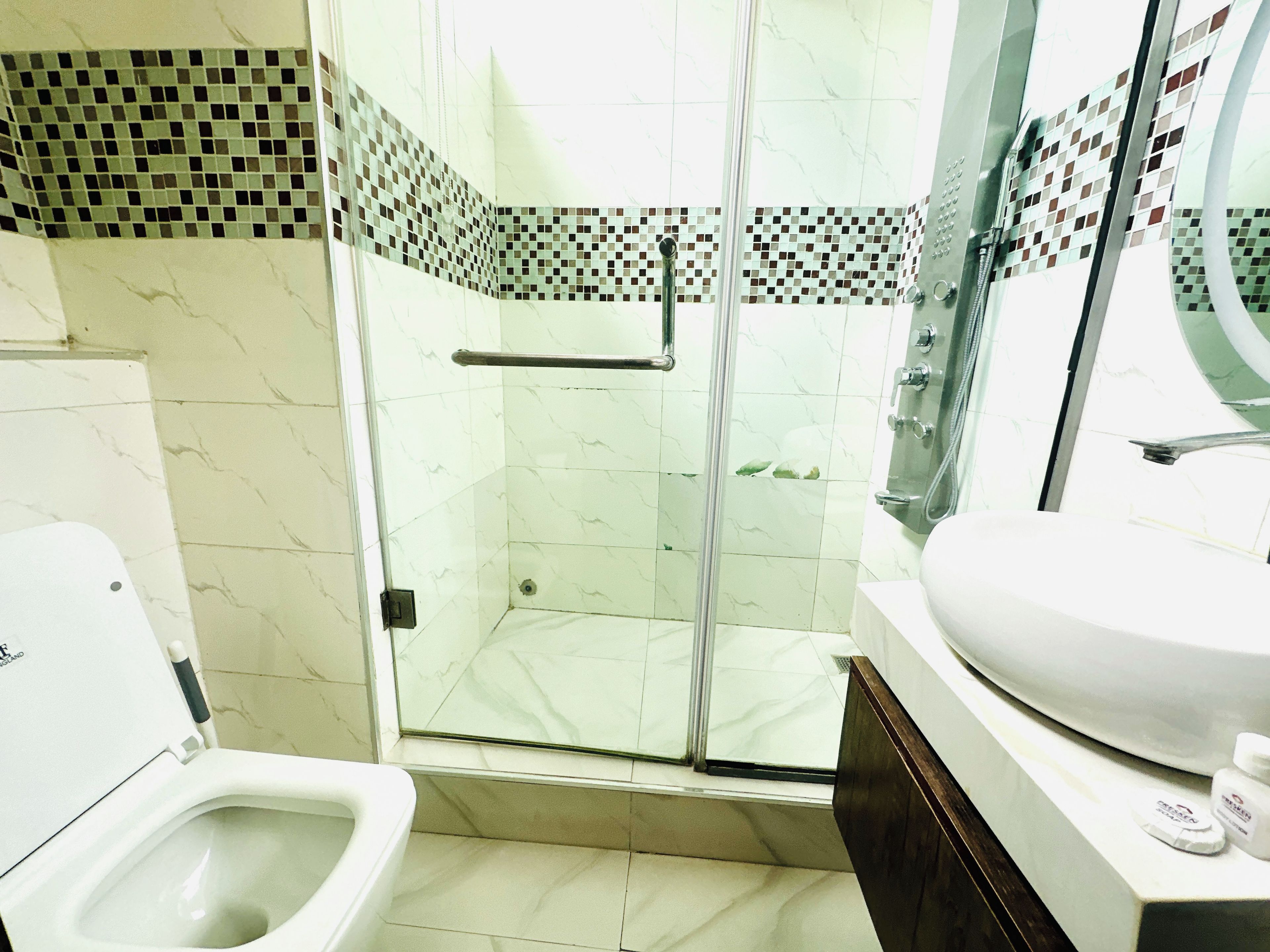 A bathroom with a glass-enclosed shower, a toilet, and a sink with a mirror.