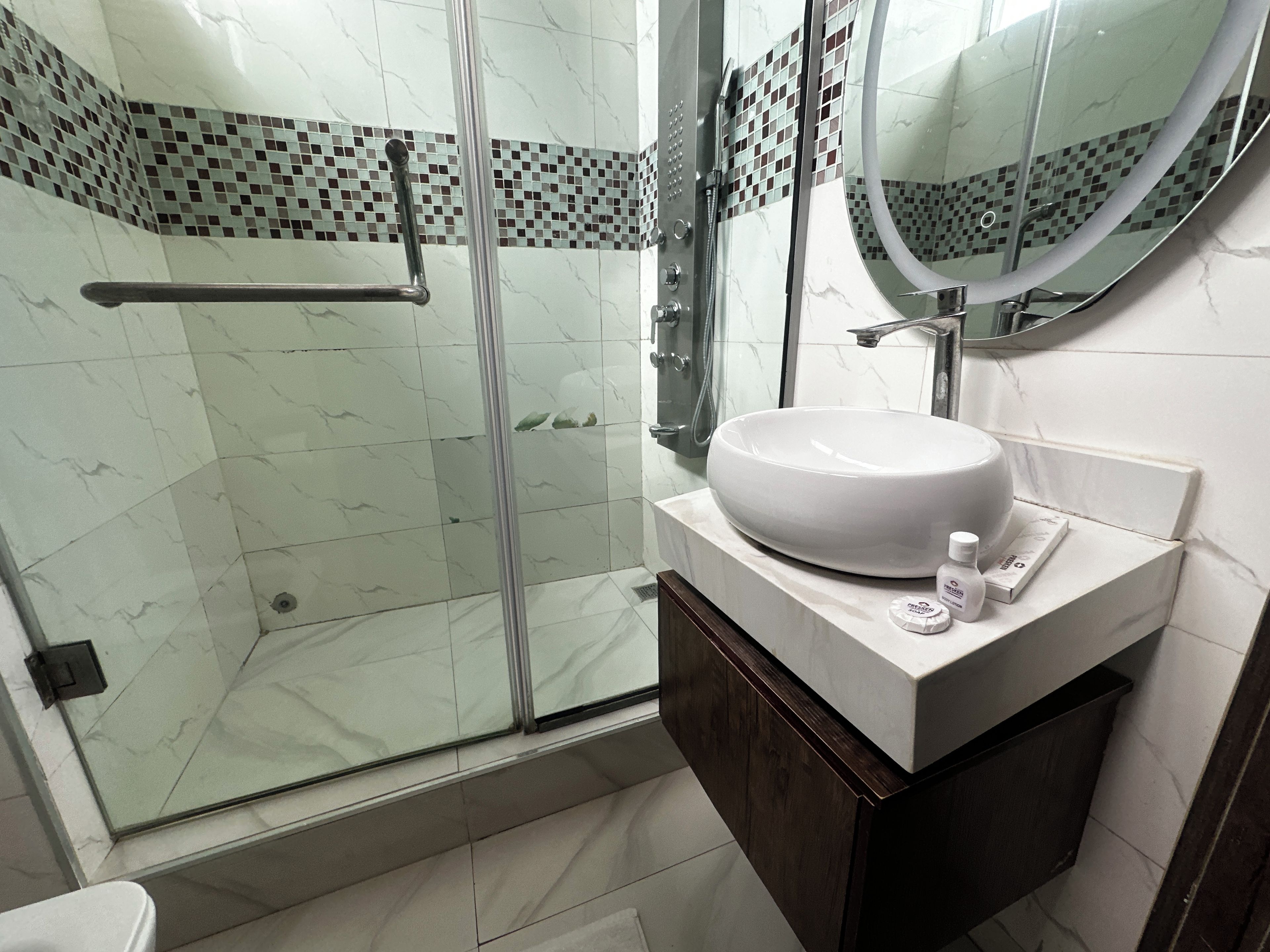 Une salle de bain moderne avec une douche à parois de verre, un lavabo blanc et un miroir au-dessus.