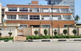 Un hotel moderno con estructura de dos pisos, techo plano y fachada en tonos blanco y marrón.