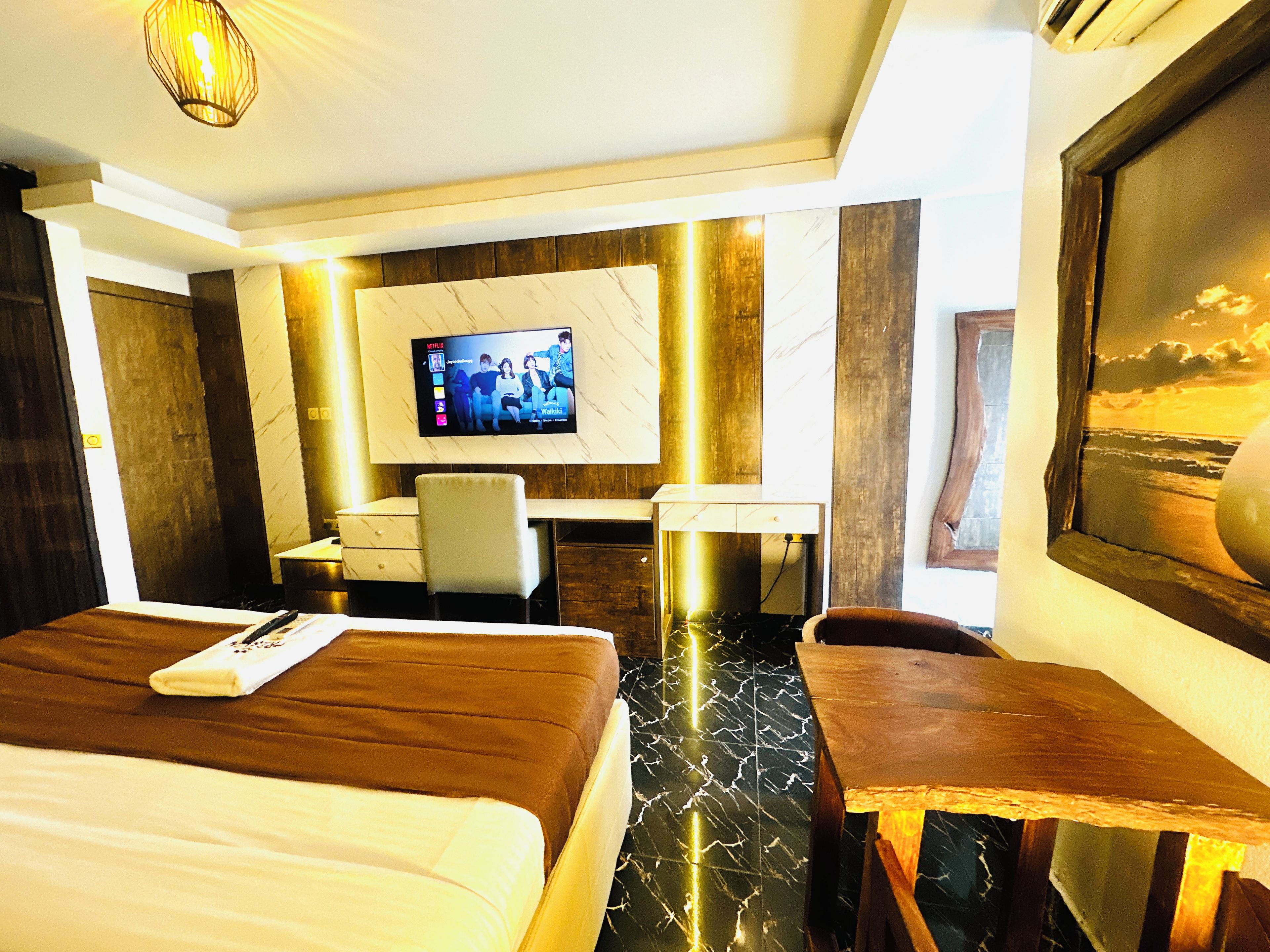 A hotel room with a bed, a desk, a chair, and a television mounted on the wall.