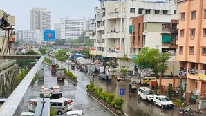 A busy urban street with buildings, vehicles, and a pedestrian walkway.