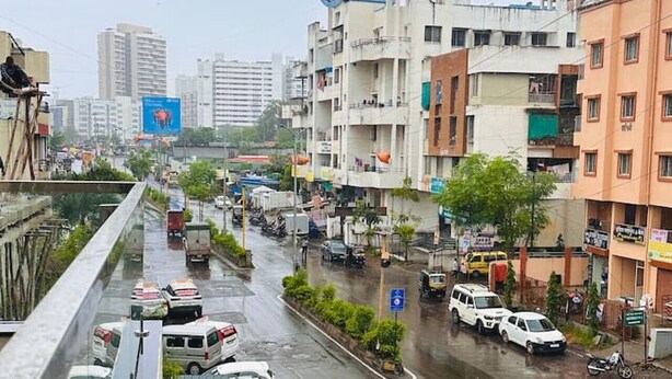 A busy urban street with buildings, vehicles, and a pedestrian walkway. - Robin`s Roost: 2BHK Modern AC Flat in Wakad, Pune (Pimpri-Chinchwad)