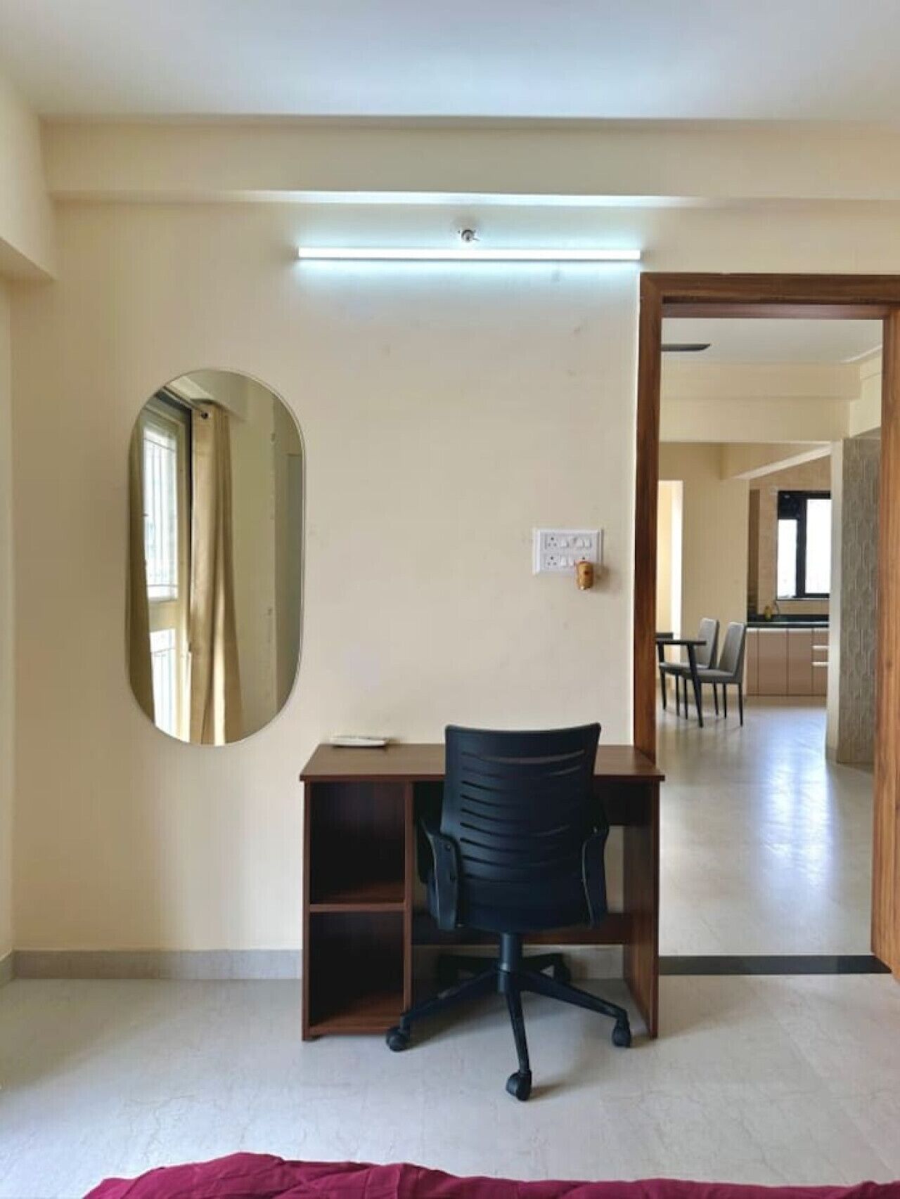 Una habitación con un escritorio, una silla y un espejo grande en la pared.