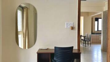 Una habitación con un escritorio, una silla y un espejo grande en la pared.