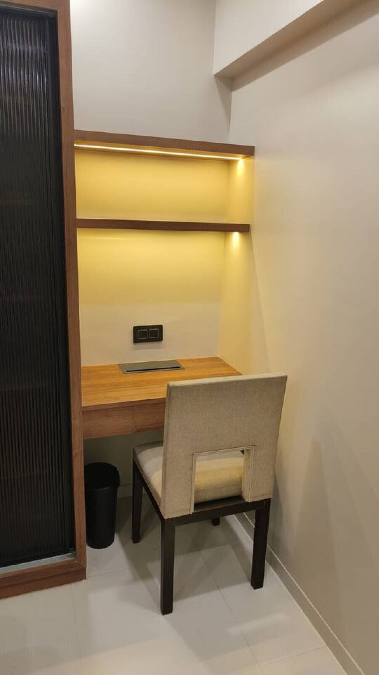 Un espace de travail compact comprenant un bureau, une chaise et une petite poubelle.