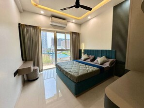Un dormitorio moderno con una cama grande, ventilador de techo, equipo de aire acondicionado y vistas a la ciudad desde la ventana.