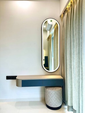 Un baño moderno con tocador, espejo y un taburete redondo pequeño.