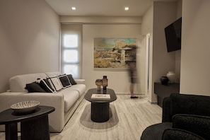 A modern living room with a sofa, a coffee table, and a painting on the wall. - Finders Top Floor Apartments (Athens)
