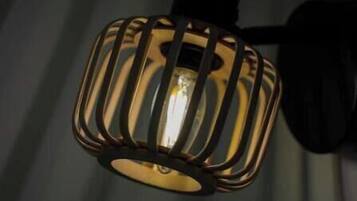 A wall-mounted light fixture with a cylindrical base and a cage-like structure around the bulb.