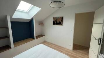 Ein Schlafzimmer mit einem Oberlicht, einem Bett, einem Kleiderschrank und einer Tür zu einem weiteren Raum.