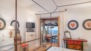 Ein Zimmer mit Bett, Fernseher, Schreibtisch und Meerblick.
