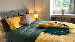 A neatly made bed with a grey headboard, multiple pillows, and a blanket.