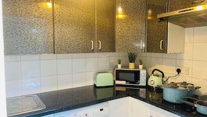 A compact kitchen with a washing machine, a microwave, a toaster, and a kettle on the countertop.