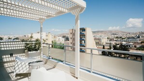 A balcony with a white pergola, potted plants, and a view of a cityscape with buildings and mountains in the distance. - Gallery Central Piraeus Port (Piraeus)
