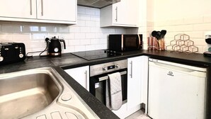 A modern kitchen with white cabinets, a black countertop, a built-in oven, a microwave, and a dishwasher. - Cosy Liverpool Apartment (Liverpool)