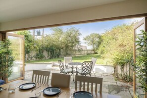 An outdoor patio with a table set for dining, chairs, and a view of a garden and trees. - 4-bed Cottage - Pets With Garden & Wood Burner (Helston)